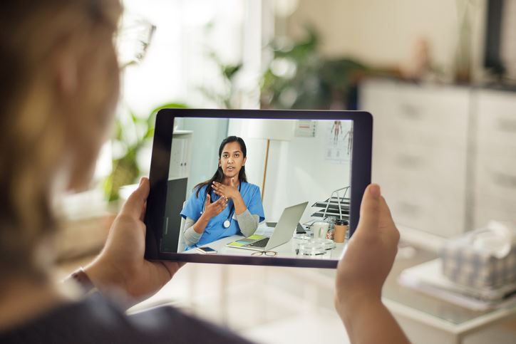 Woman holding up her tablet for a telehealth call